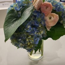 close up of pink, peach and blue flowers in a vase on a desk